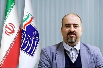 وحید یزدانیان در کنار پرچم ایران و پرچم سازمان فضایی